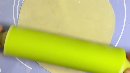 Rolling out round pieces of raw dough with a rolling pin to make patties. Top view.