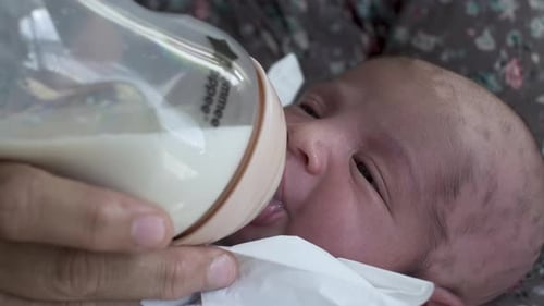 Bebé recién nacido que bebe leche materna de biberón. De cerca, bloqueado