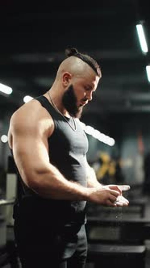Muscular Athlete Chalking Hands Before Weightlifting Gripping Barbell Tightly Preparing for