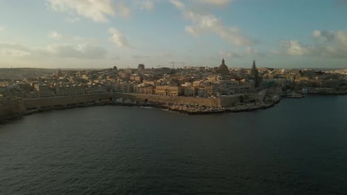 Panoramic view over Valletta’s waterfront and cityscape at dawn, with a soft morning light creating