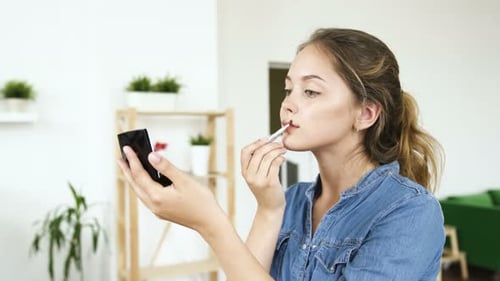 Young Woman Applies Makeup in Bright Home Setting