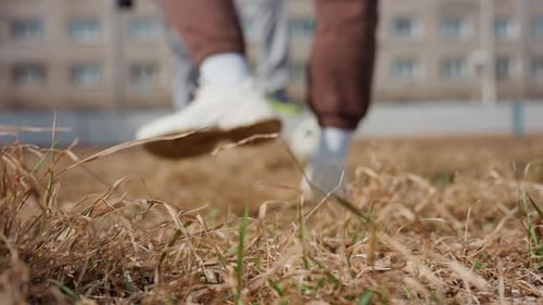 Footsteps on Dry Grass Someone Strides Over Parched Grass with City Backdrop Behind Figure Moves
