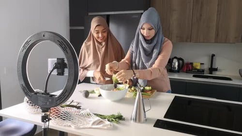 Deux vloggers culinaires musulmans expliquent comment préparer une salade à la cuisine.