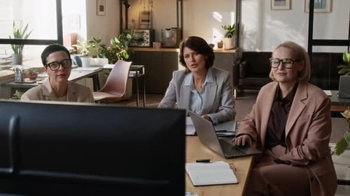 Three Women Having Online Business Video Conference at Desk in Modern Office