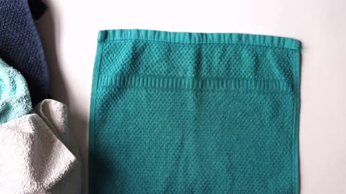 Close up of hands folding laundry. Soft turquoise towel. Household chores