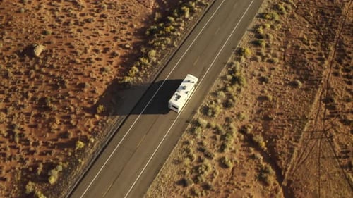 Topdown drone aerial footage of RV driving along road on American road trip in the desert, near cany