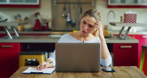 Woman working at laptop in bright kitchen