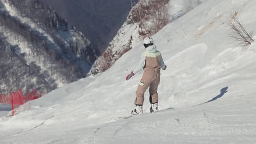 Ein Snowboarder fährt zusammen auf einer Skipiste im Extremwintersport eines Skigebiets am Berghang