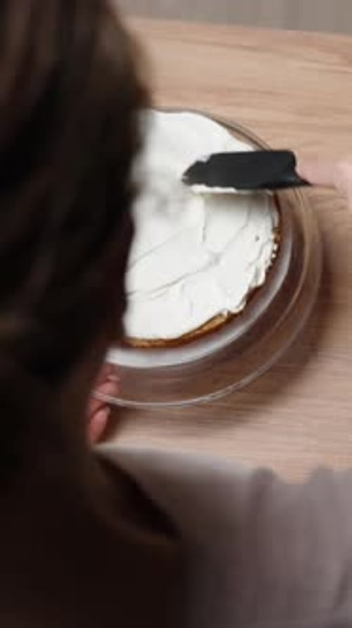 Vertical video. The camera is shooting from behind and above a female pastry chef as she prepares