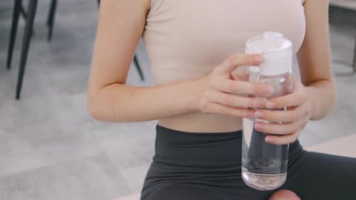 Woman Drinks Water after Workout with Headphones