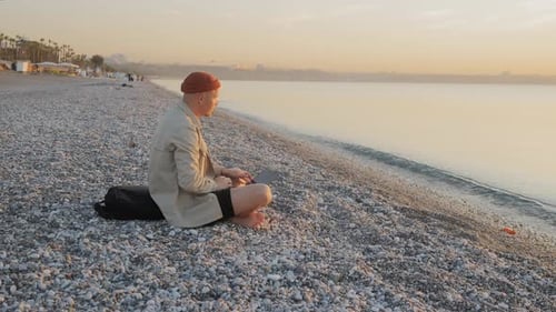 Digital Nomad of the Millennial Generation is Working on a Laptop on the Beach