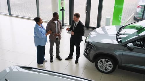 Couple Shaking Hands with Car Dealer in a Showroom
