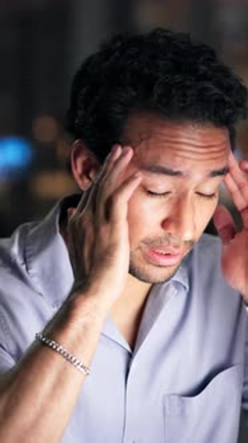 Young Man with Headache Massaging Temples at Night