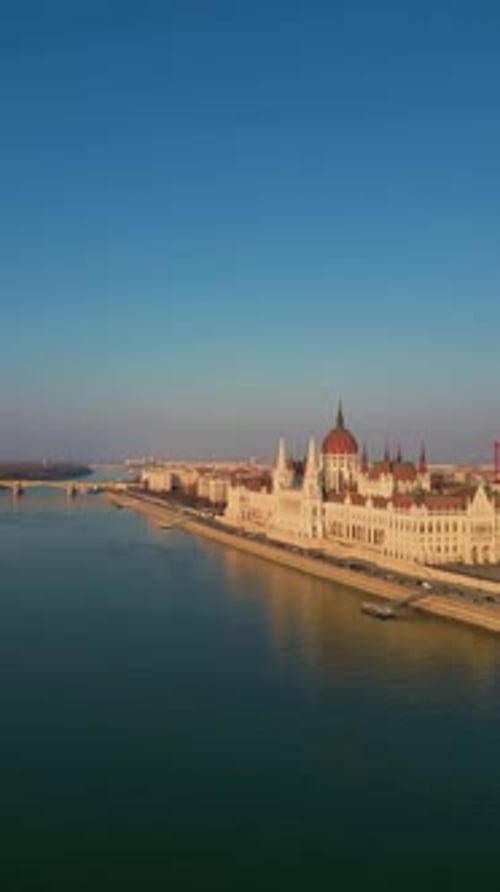 Hungarian Parliament Building reflecting on Danube river in Budapest vertical aerial drone view