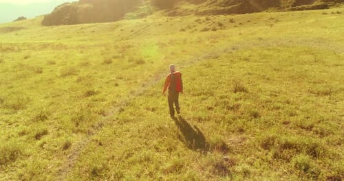 Flight Over Backpack Hiking Tourist Walking Across Green Mountain Field Huge Rural Valley at Summer