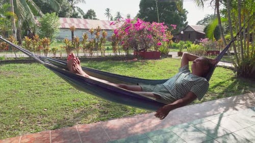 Woman is resting in hammock and enjoying summer in garden