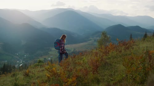 Millennial woman reaches mountain peak hiking on summer vacation adventure travel
