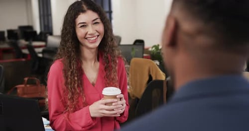 Two happy diverse creative colleagues in discussion in casual office, slow motion