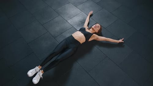 Athletic Young Woman in Black Sportswear Doing Stretching in Gym