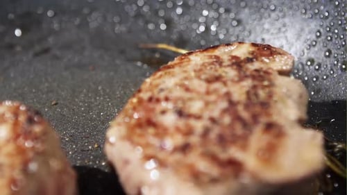 Close Up of Two Fried Piece of Meat on the Hot Pan Fat