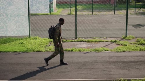 Young Man Walks Along a Street with Backpack