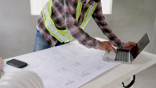 Anonymous Person Wear green reflective vest and safety helmet on house under construction.