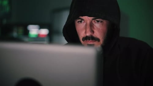 Close Up Portrait of One Hacker Looking the Screen of a Laptop Computer Typing the Code to Breack