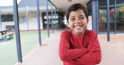 In a school courtyard, a young boy smiles broadly