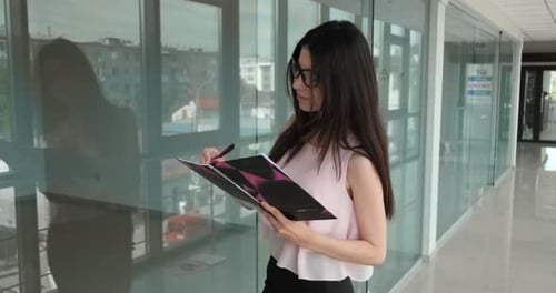 Woman Writes in Notebook in Modern Office
