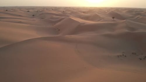 Drone flying towards the sunset in Abu Dhabi desert, United Arab Emirates. Aerial view