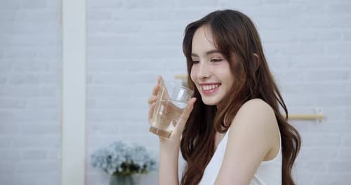 Beautiful Woman Drinks Water in Bright Home Setting