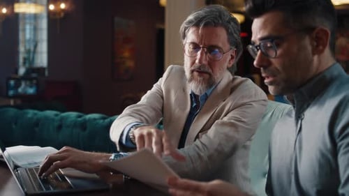 Male Coworkers Studying Papers in Office Cafe