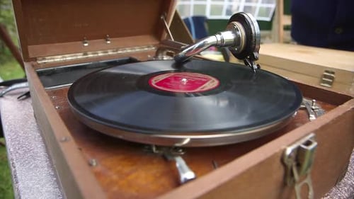 Record schaltet ein antikes Grammophon in einer Holzkiste ein. Musik spielt.