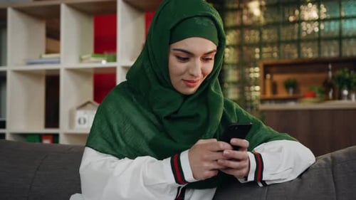 Close Up Muslim Woman Use Mobile Phone in the Hands Wearing a Hijab at Home Sofa Smart Phone Arabic