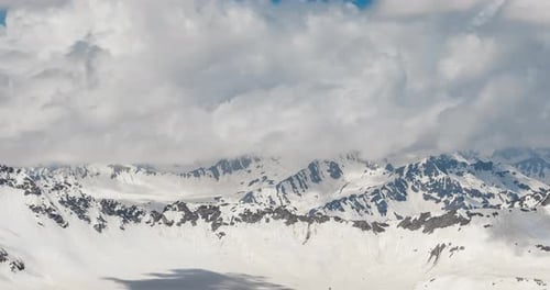 Air flight through mountain clouds over beautiful snow-capped peaks of mountains and glaciers.