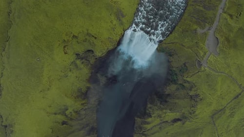 Top-down aerial view of the amazing waterfall surrounded by endless grassy meadows.