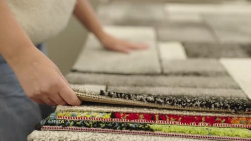 Woman Comparing Carpet Texture and Rug Samples in Home Furnishing Store for Interior Decoration