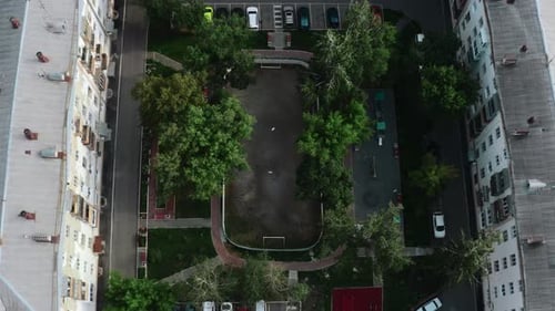 Person on playground in courtyard of modern houses. Stock footage. Top view of modern playground