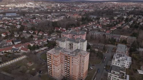 Flying over with a drone three residential apartment buildings in the middle of a town.