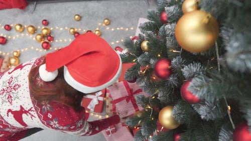 Woman Placing Gift Under Christmas Tree