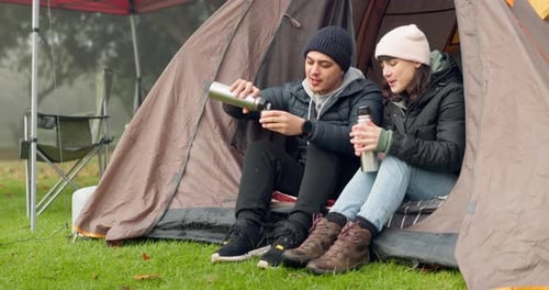 Couple Sits in Tent and Drinks Beverage