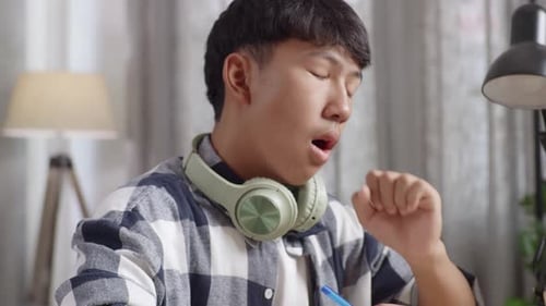 Tired Asian Teenager Yawning And Sleep On The Table At Home After Doing Home Work