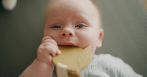 Closeup of Baby Chewing Teether on Playmat
