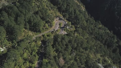 White Car Driving on Winding Mountain Road Surrounded By Lush Green Forest
