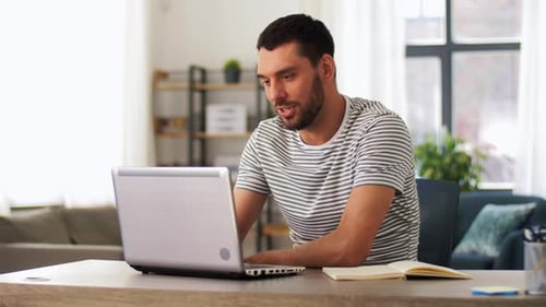 Man Working on Laptop at Desk in Bright Room