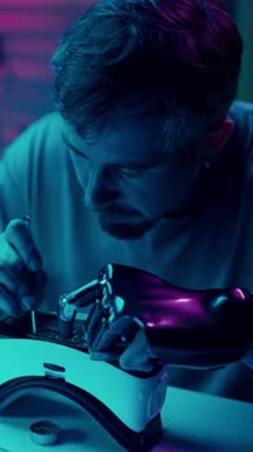Young Adult Repairs Futuristic Device With Prosthetic Hand