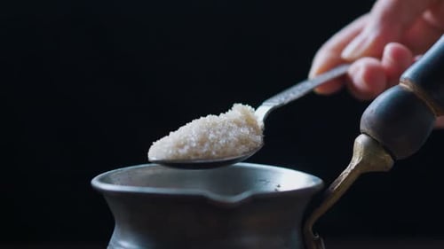 Pouring Sugar Into Coffee Cezve with Teaspoon Close Up Side View
