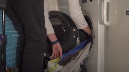 Person Loading Laundry into Washing Machine at Home