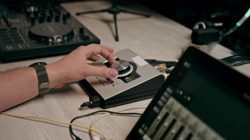 professional recording studio sound engineer with finger adjusts volume level on mixing console