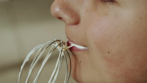 Woman Licks Frosting from Metal Whisk Close Up